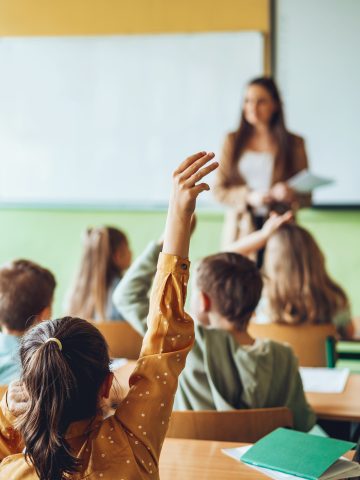 Skole pige med hånd oppe i skole