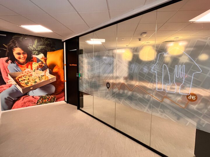 Brandet vægdesign og glasparti med frostet folie og udskåret tekst hos Just Eat kontor.